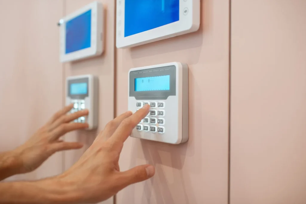 Įsilaužėlis bando atidaryti duris, nuo kurio apsaugotų moderni namų signalizacija.